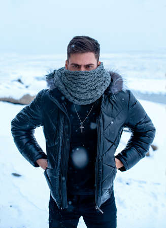A man in winter on a background of snow in black clothesの写真素材