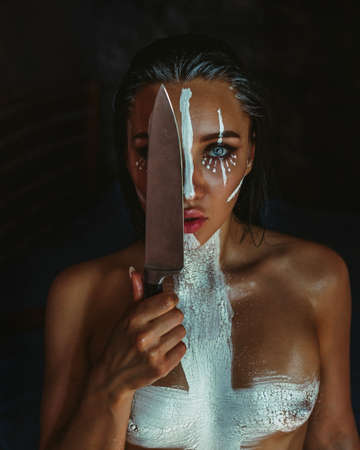 A brunette girl dangerously licks the blade of a knife