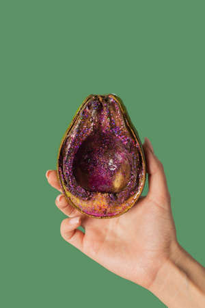 Colored avocado on a green background.Added glitter. Fun, minimal and whimsical color still life...