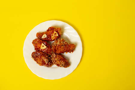 Crispy sesame chicken legs with sticky sweet Asian sauce on a plateの写真素材