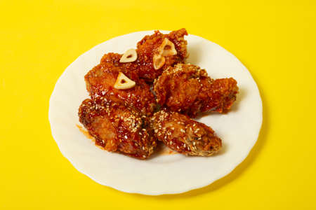 Crispy sesame chicken legs with sticky sweet Asian sauce on a plateの写真素材