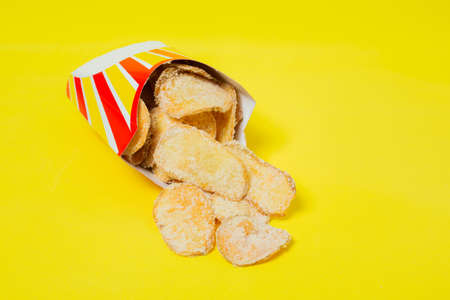 French fries in eco-friendly packaging on a yellow background. Unhealthy fast food.の写真素材