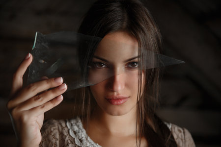 Portrait of a brunette girl looking through a shard of glass,の写真素材