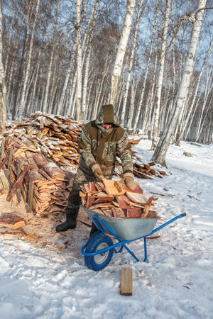 A man drives a cart with firewood, in winter in a Russian villageの写真素材