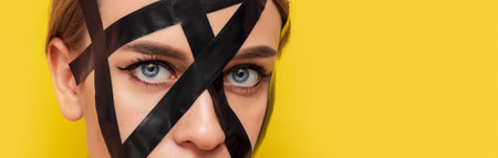 Portrait of a girl in bdsm style in duct tape, fashion, cosmetology, on a yellow background