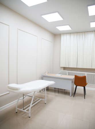 Modern interior of the cosmetology office with a full-electrical facial beauty bed and chair, and shelves with skincare products in a beauty salon.の写真素材