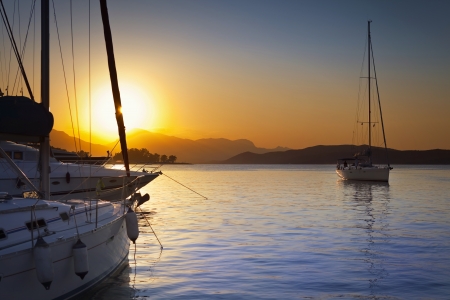 Sailing ships in Poros harbor in Greece at sunsetの写真素材