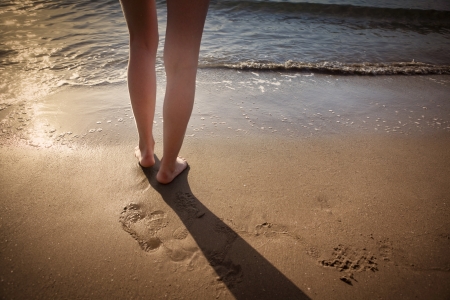 Legs of a young woman on a beach in Greece at sunset