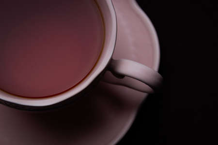 Ceramic Tea Cup on Black Background. Pink cup with black teaの写真素材