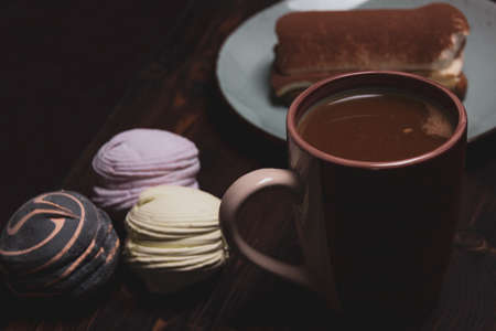 Morning breakfast of coffee and sweet marshmallows and tiramisu on a wooden background.