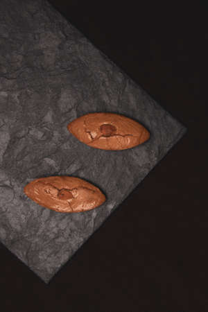 Two almond biscuits on a stone slab.