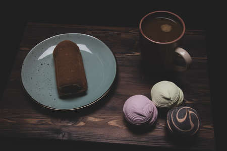 Morning breakfast of coffee and sweet marshmallows and tiramisu on dark background.