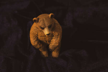 Toy brown bear on a dark background. Plastic toy