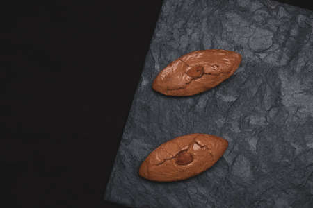 Two almond biscuits on a stone slab.