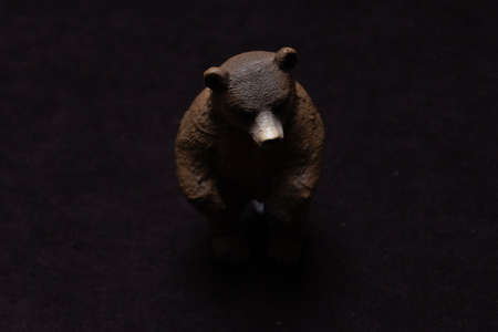 Toy brown bear on a dark background. Plastic toy