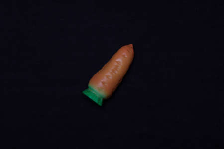 Toy carrot on a dark background. Plastic toyの写真素材