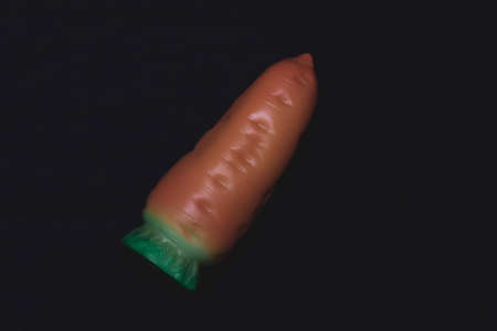 Toy carrot on a dark background. Plastic toy