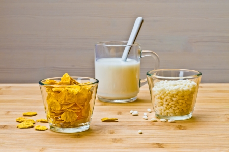 Breakfast with milk, corn flakes and puffed rice on a wooden tableの写真素材