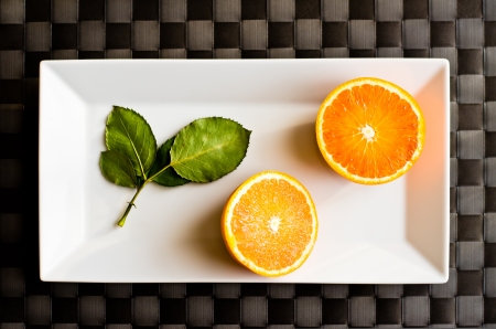 oranges cut in half on rectangular white plate on checkered tablecloth blackの写真素材