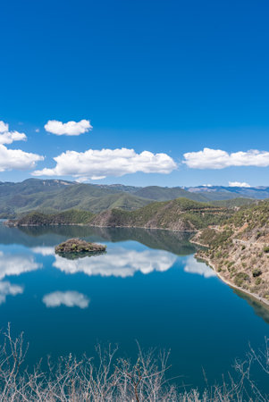 The reflection of blue sky and white clouds on the water surface of Lugu Lake in Chinaの写真素材