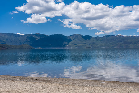 The reflection of blue sky and white clouds on the water surface of Lugu Lake in Chinaの写真素材