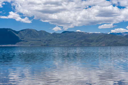 The reflection of blue sky and white clouds on the water surface of Lugu Lake in Chinaの写真素材