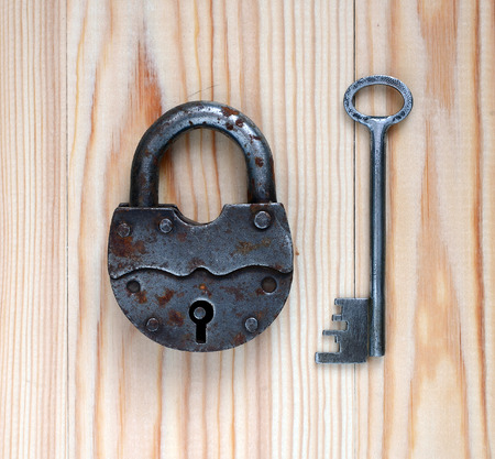 Padlock and key on a wooden background.の写真素材