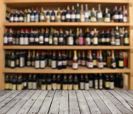 Wooden board empty table in front of blurred background alcohol bottle.