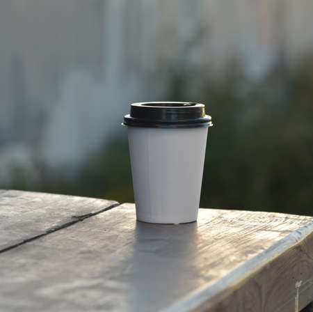 A paper cup of coffee on a wooden table.の写真素材