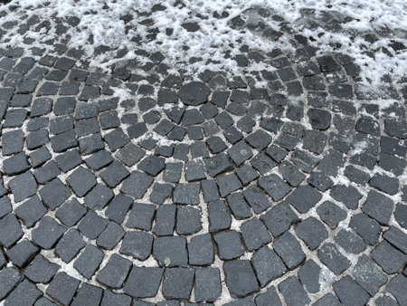 White Snow lies on an old cobblestone pavementの写真素材
