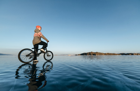 Girl standing on a bmx on the beautiful and dangerous ice.の写真素材