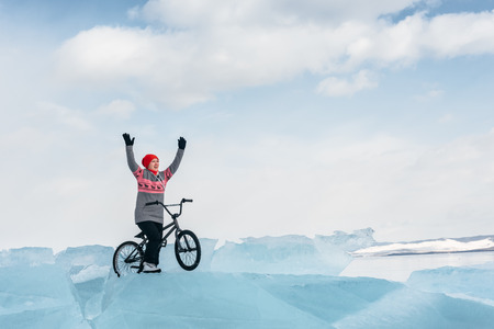 Girl standing on a bmx on the beautiful and dangerous ice and enjoys a successful campaign. Ice the deepest lake in the world. This is Lake Baikal.の写真素材