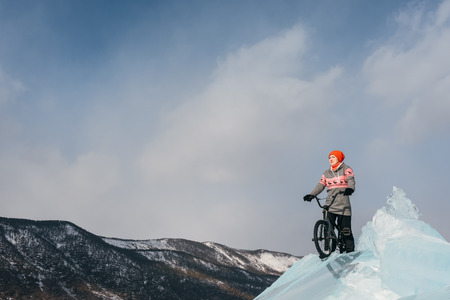 Girl standing on a bmx on the beautiful and dangerous ice. Ice the deepest lake in the world. This is Lake Baikal.の写真素材