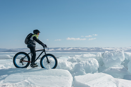 Fatbike (also called fat bike or fat-tire bike) - Cycling on large wheels. A cyclist sits on the bike on the ice.の写真素材