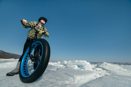 Fatbike (also called fat bike or fat-tire bike) - Cycling on large wheels. Extreme girl sitting on the bike on snow melted ice. The Lake Baikal.の写真素材