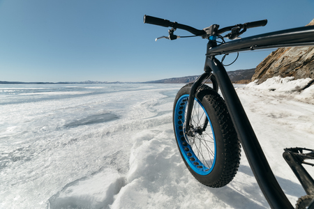 Fatbike also called fat bike or fat-tire bike - Cycling on large wheels. Bike standing on the ice of Lake Baikal, near frozen around the island. With views of the mountains and the endless ice.の写真素材