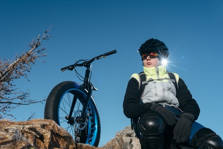 Fatbike also called fat bike or fat-tire bike - Cycling on large wheels. Traveller cyclist sits on top of the mountain. He is resting on a trip looking at the sunset.の写真素材