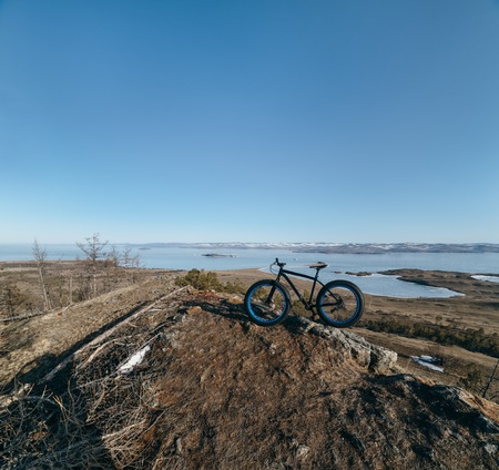 Fatbike also called fat bike or fat-tire bike - Cycling on large wheels. Bike stands on top of the mountain, amid the scenic frozen Lake Baikal.の写真素材