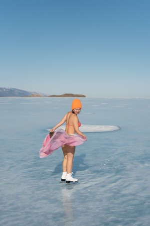 Girl extreme sportswear in a swimsuit on the ice. Ice lady. A female beginner skater skates and...