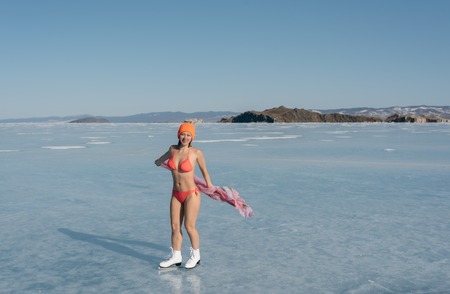 Girl extreme sportswear in a swimsuit on the ice. Ice lady. A female beginner skater skates and poses on skates, and tans. She has a beautiful body, strong health and great courage. Its freezing outside.の写真素材