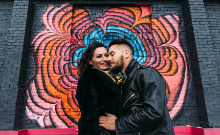 Wedding in the style of rock. Rocker or Biker wedding. Guys with stylish leather jackets. Its a rocknroll baby! A sweet couple is photographed against the background of graffiti.の写真素材
