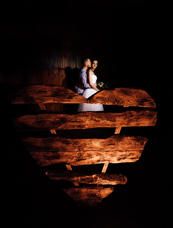 Wedding in the style of rock. Rocker or Biker wedding. Guys with stylish leather jackets. Its a rocknroll baby. Sweet couple in a photo studio. Steep shooting in a wooden location. Around the bulb of warm light. A huge wooden heart.の写真素材