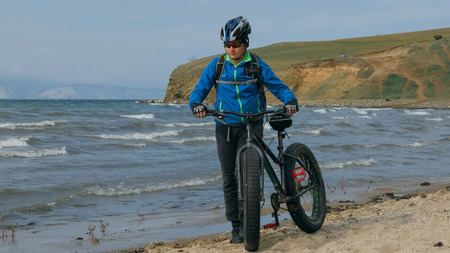 Fat bike also called fatbike or fat-tire bike in summer driving on the beach. The guy is going straight on the beach. On the sand on such a bike ride is not difficult.の写真素材