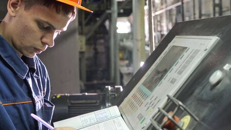 RUSSIA, ANGARSK - JUNE 8, 2018: Operator monitors control panel of production line. Manufacture of plastic water pipes of the factory. Process of making plastic tubes on machine tool with the use of water and air pressure.のeditorial素材