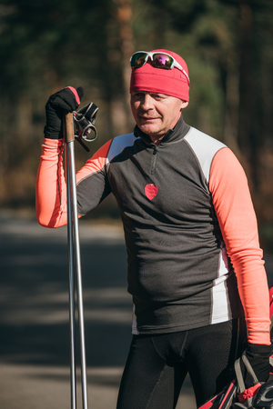Training an athlete on the roller skaters. Biathlon ride on the roller skis with ski poles, in the helmet. Autumn workout. Roller sport. Adult man riding on skates.の写真素材