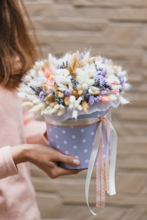 Colorful bouquet of different dried flowers deadwood flowers in the hands of a florist woman. Rustic flower background. Craft bouquet of flowers.の写真素材