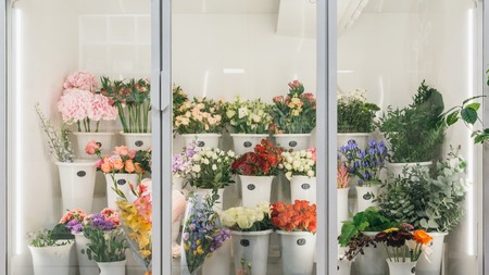 Flower shop concept. Different varieties fresh spring flowers in refrigerator room for flowers. Bouquets on shelf, florist business.の写真素材