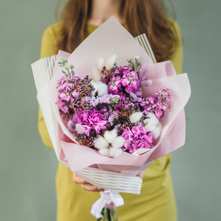 Colorful bouquet of different fresh flowers in the hands of a florist woman. Rustic flower background. Craft bouquet of flowers.の写真素材