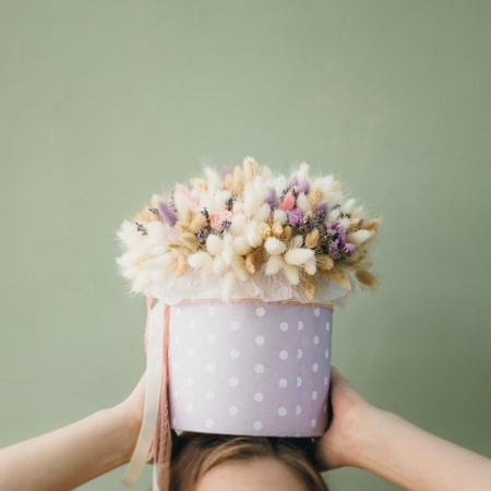 Colorful bouquet of different dried flowers deadwood flowers in the hands of on the head woman. Rustic flower background. Craft bouquet of flowers.の写真素材