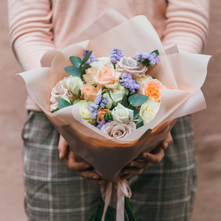 Colorful bouquet of different fresh flowers in the hands of a florist woman. Rustic flower background. Craft bouquet of flowers.の写真素材